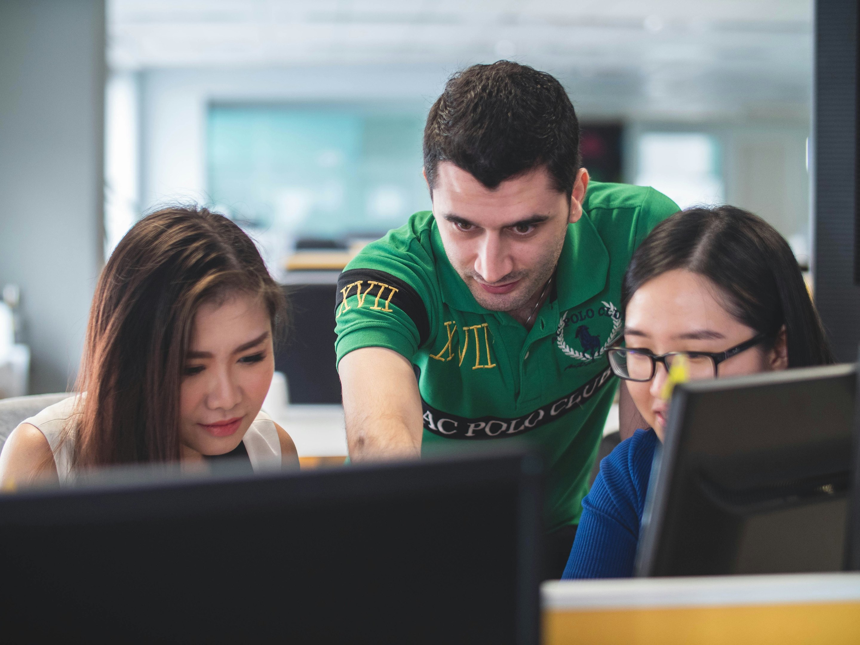 An instructor helping two students at their computers